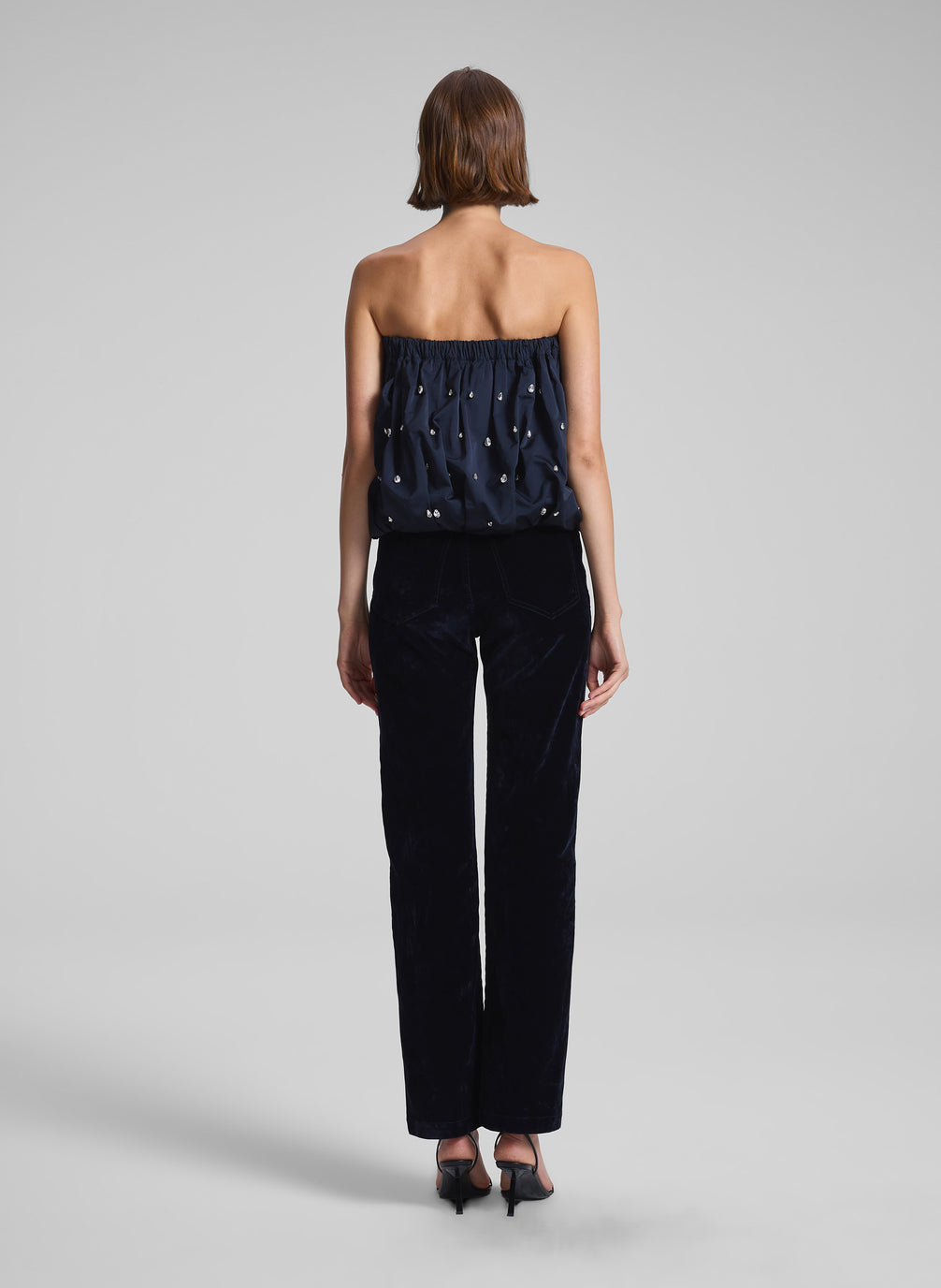 woman wearing navy blue embellished strapless top and navy blue velvet pants