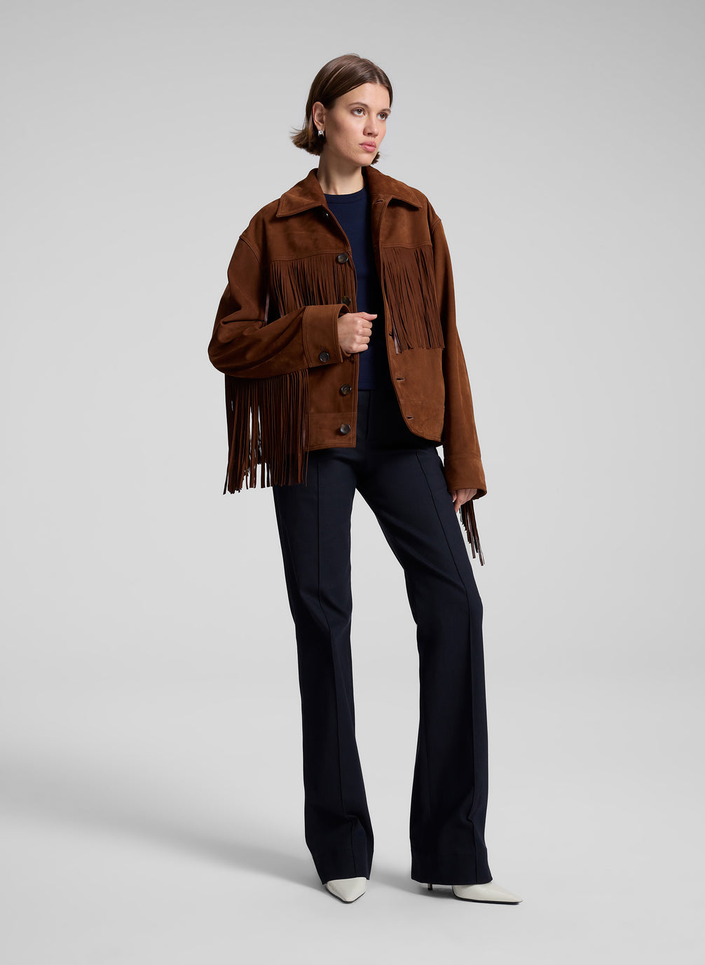 woman wearing brown suede jacket and navy blue top and navy blue pants