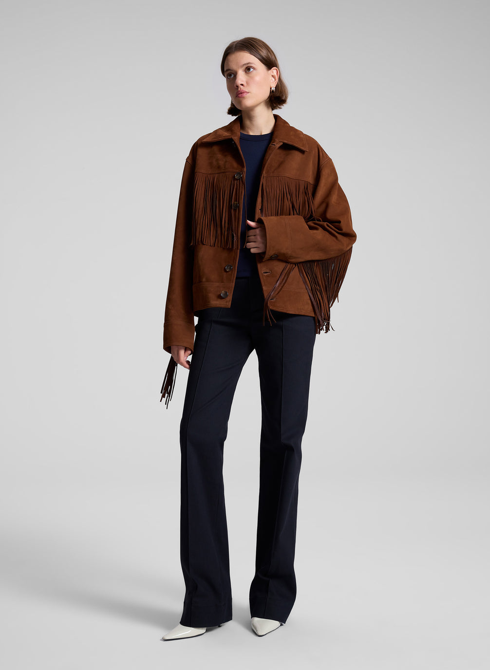 woman wearing brown suede jacket and navy blue top and navy blue pants