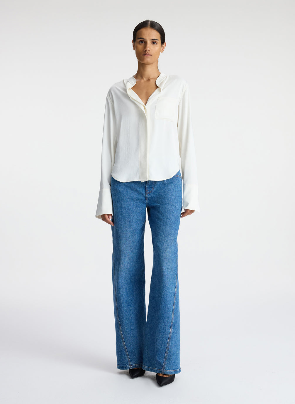 front view of woman wearing white satin long sleeve button down and medium blue wash denim jeans