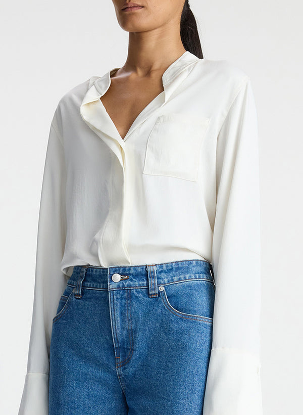 detail view of woman wearing white satin long sleeve button down and medium blue wash denim jeans