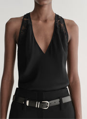 Person wearing a black sleeveless top and black pants with a belt on a plain background