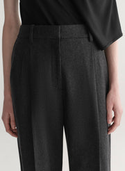 Woman wearing a black one-shoulder top and wide-leg pants on a white background