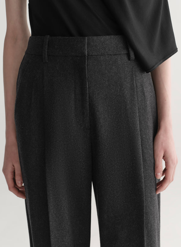 Woman wearing a black one-shoulder top and wide-leg pants on a white background