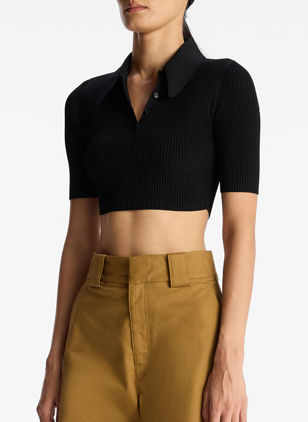 detail view of woman wearing black cropped collared knit shirt and tan cargo pants