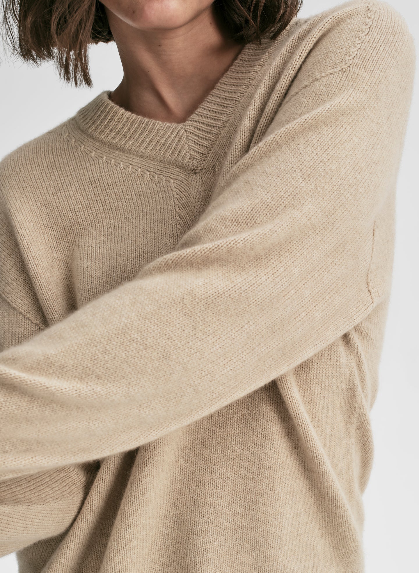 Close-up of a person wearing a beige sweater on a white background