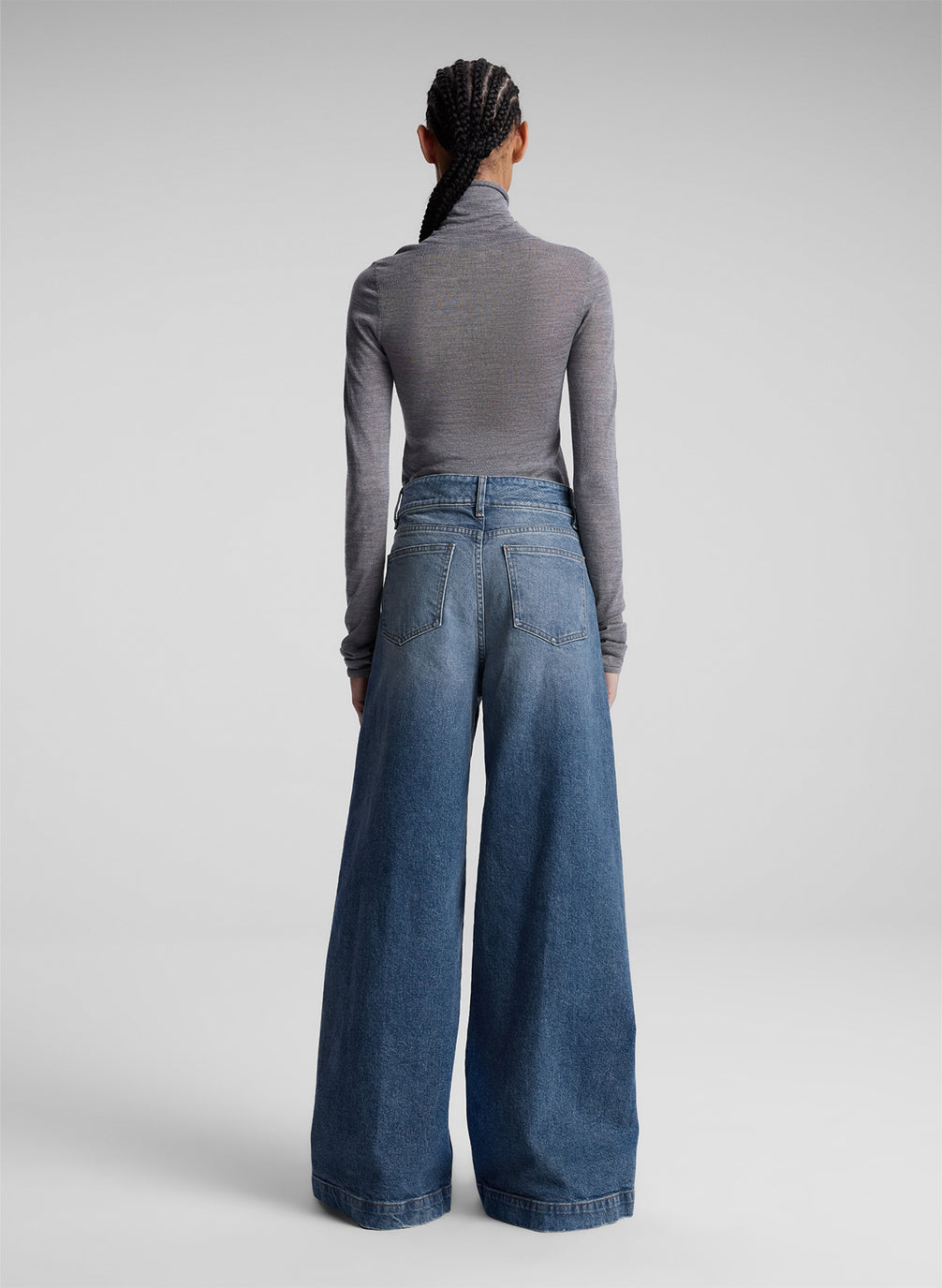 woman wearing grey turtleneck and wide leg medium blue jeans