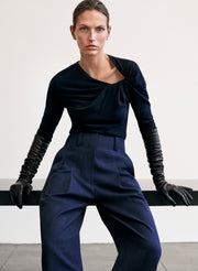 Woman wearing a dark blue outfit with gloves against a plain background