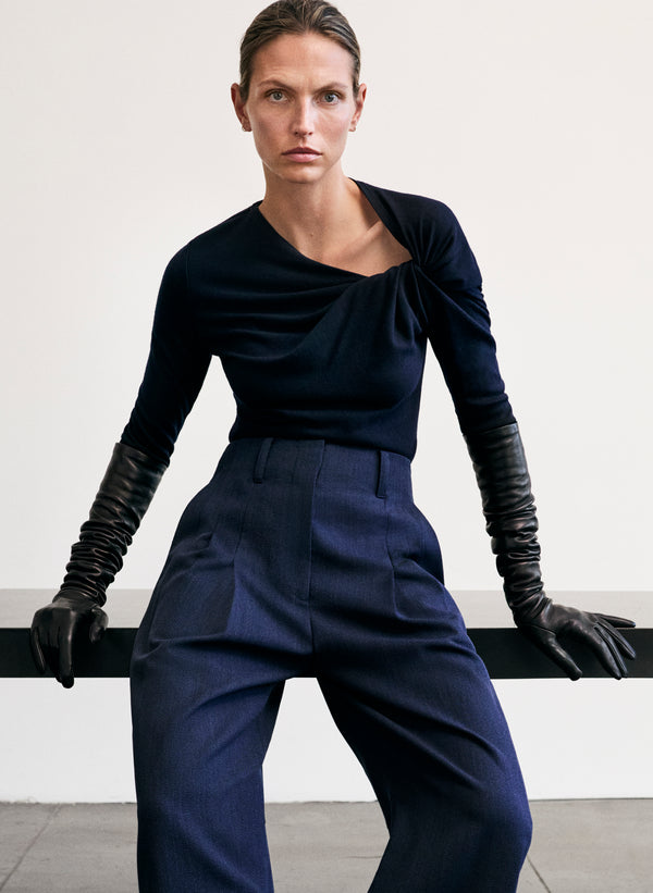 Woman wearing a dark blue outfit with gloves against a plain background