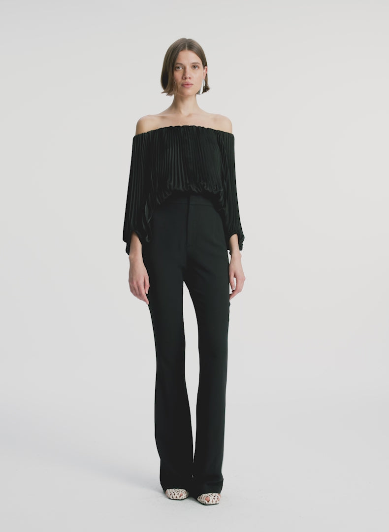 video view of woman wearing black satin pleated off the shoulder top with black pants