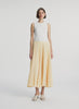 video view of woman wearing white tank top and yellow pleated midi skirt