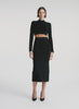 video view of woman wearing black long sleeve crop top with scallop detailing and matching black scalloped detailing knit midi skirt
