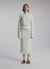 video view of woman wearing white pullover sweater and matching midi skirt