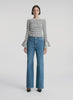 video view of woman wearing striped long bell sleeve knit top and medium blue wash denim jeans