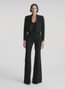 360  view of woman wearing black camisole top, black cropped jacket,  and black flared pants