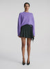video view of woman wearing purple sweater and black pleated mini skirt
