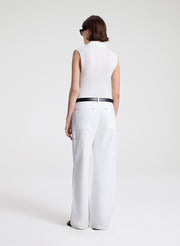 Person wearing a white sleeveless top and wide-leg pants on a plain background
