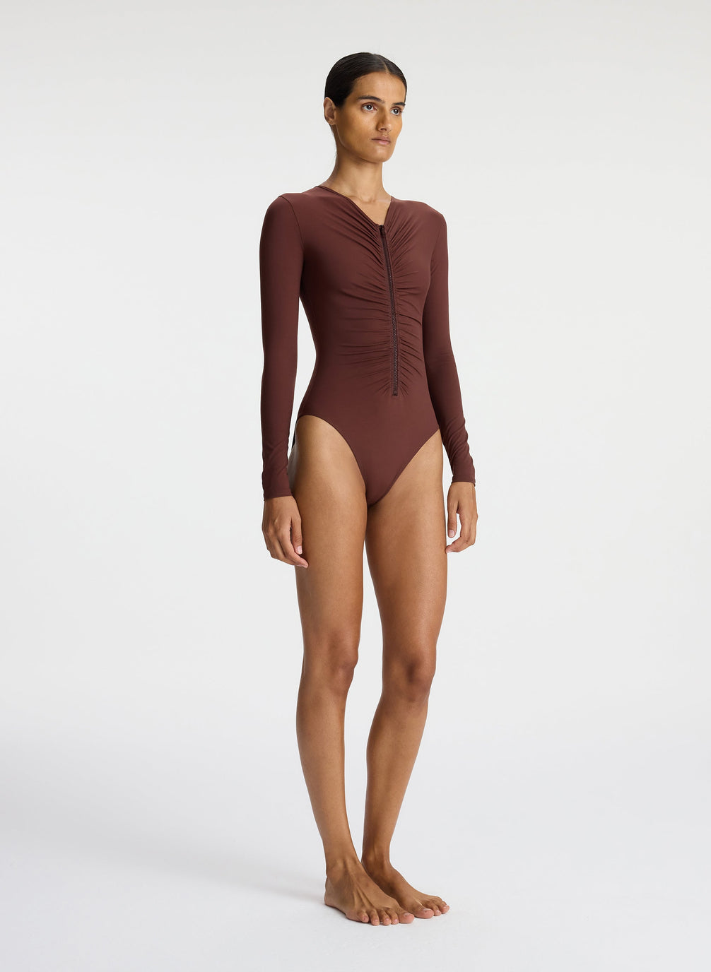 side view of woman wearing brown long sleeve zip front swimsuit