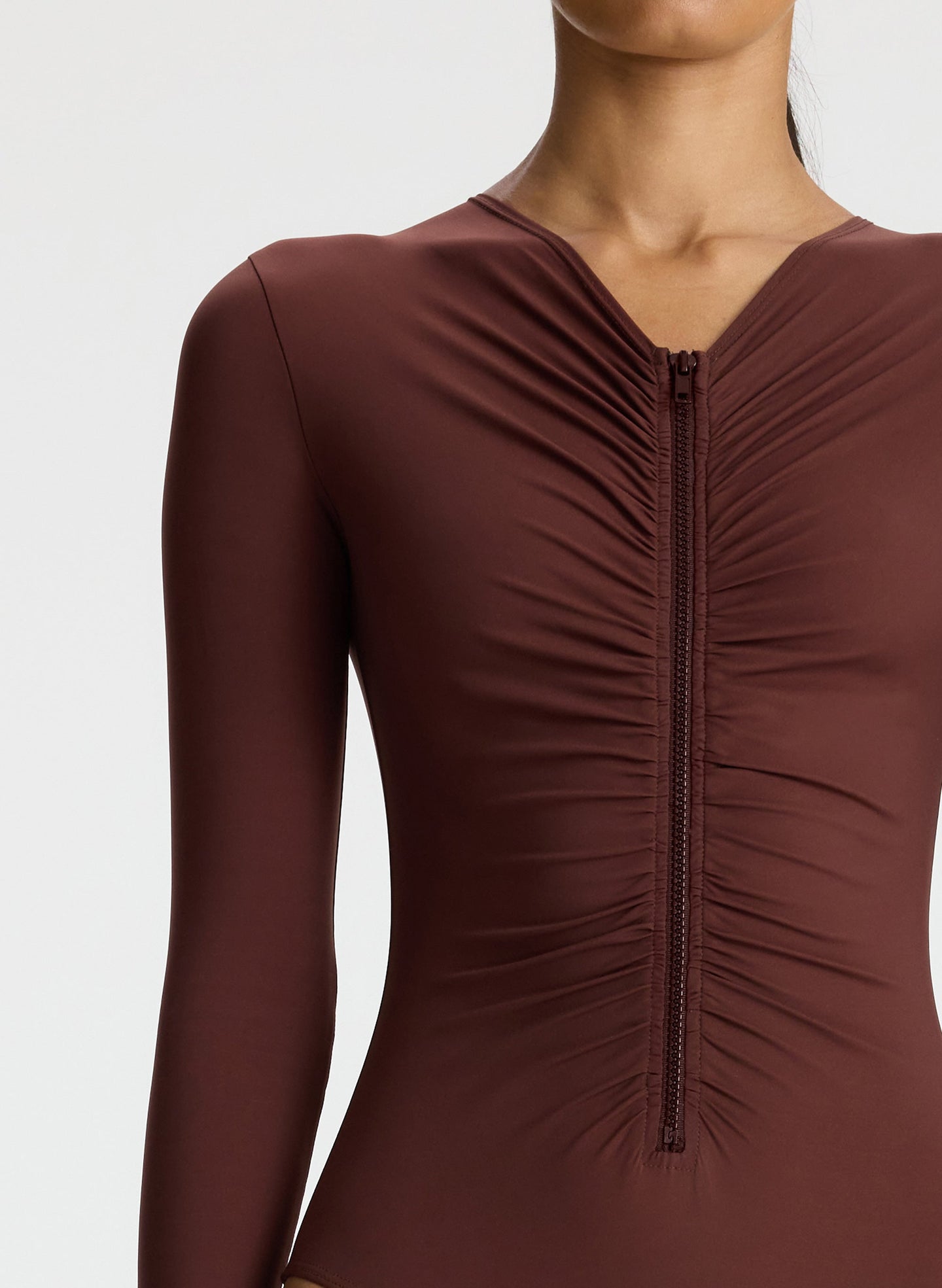 detail view of woman wearing brown long sleeve zip front swimsuit