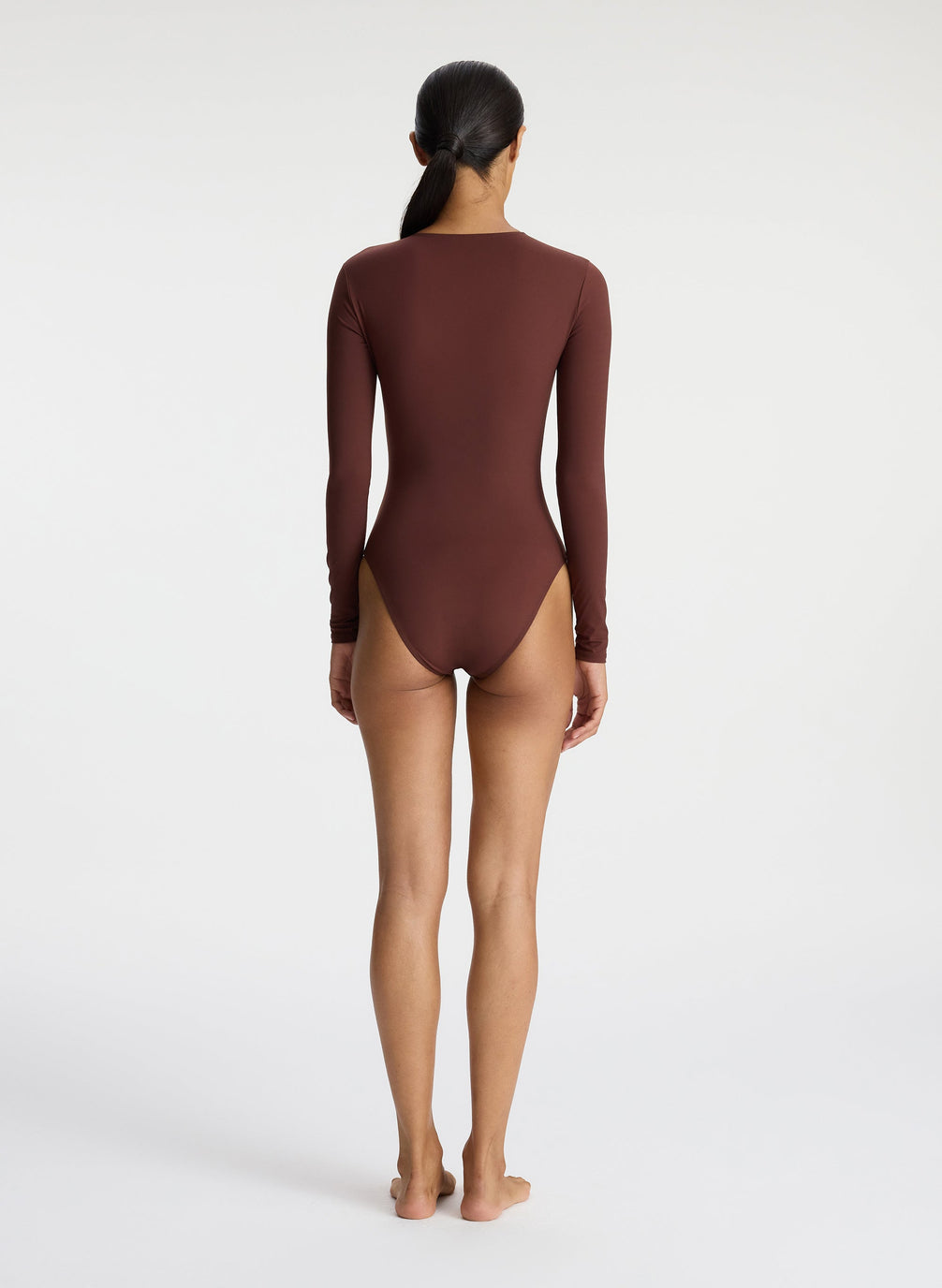 back view of woman wearing brown long sleeve zip front swimsuit