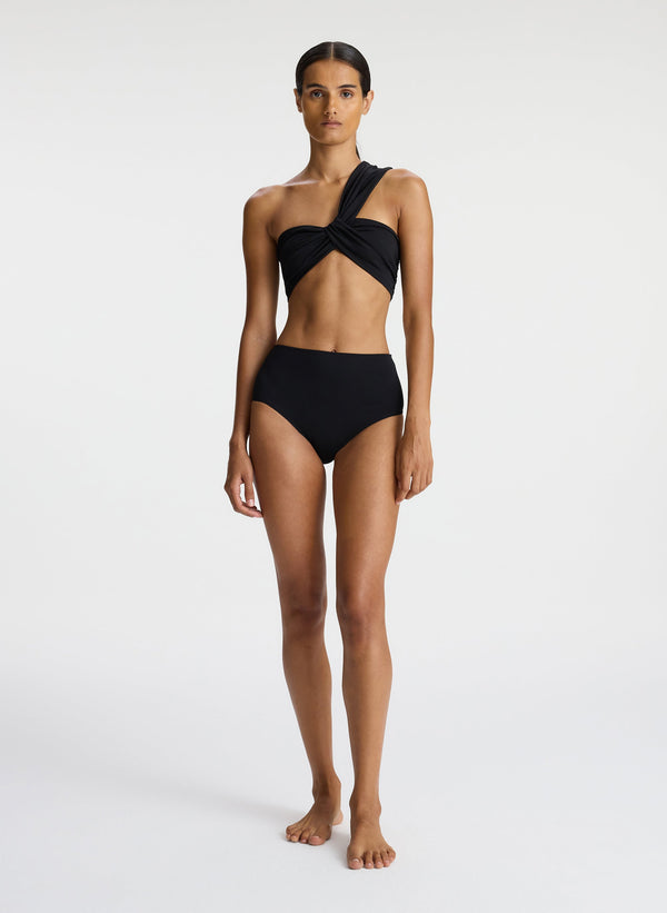 front view of woman wearing black one shoulder swim top and black bikini bottom