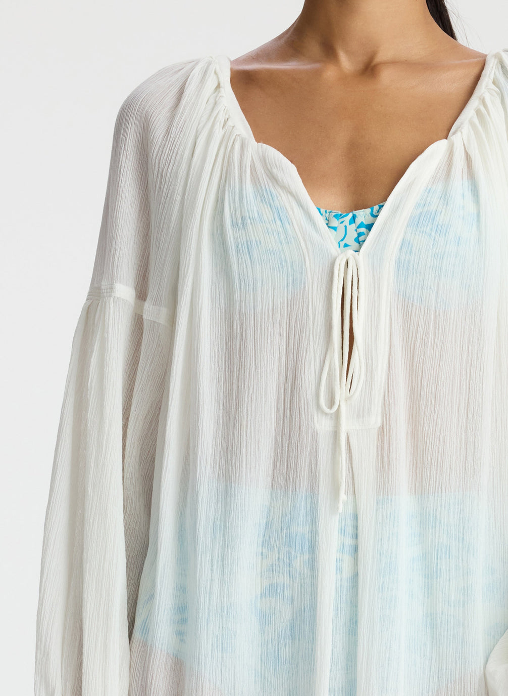 detail view of woman wearing white sheer swim cover up dress