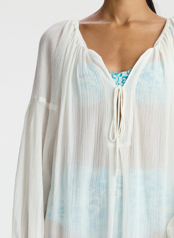 detail view of woman wearing white sheer swim cover up dress