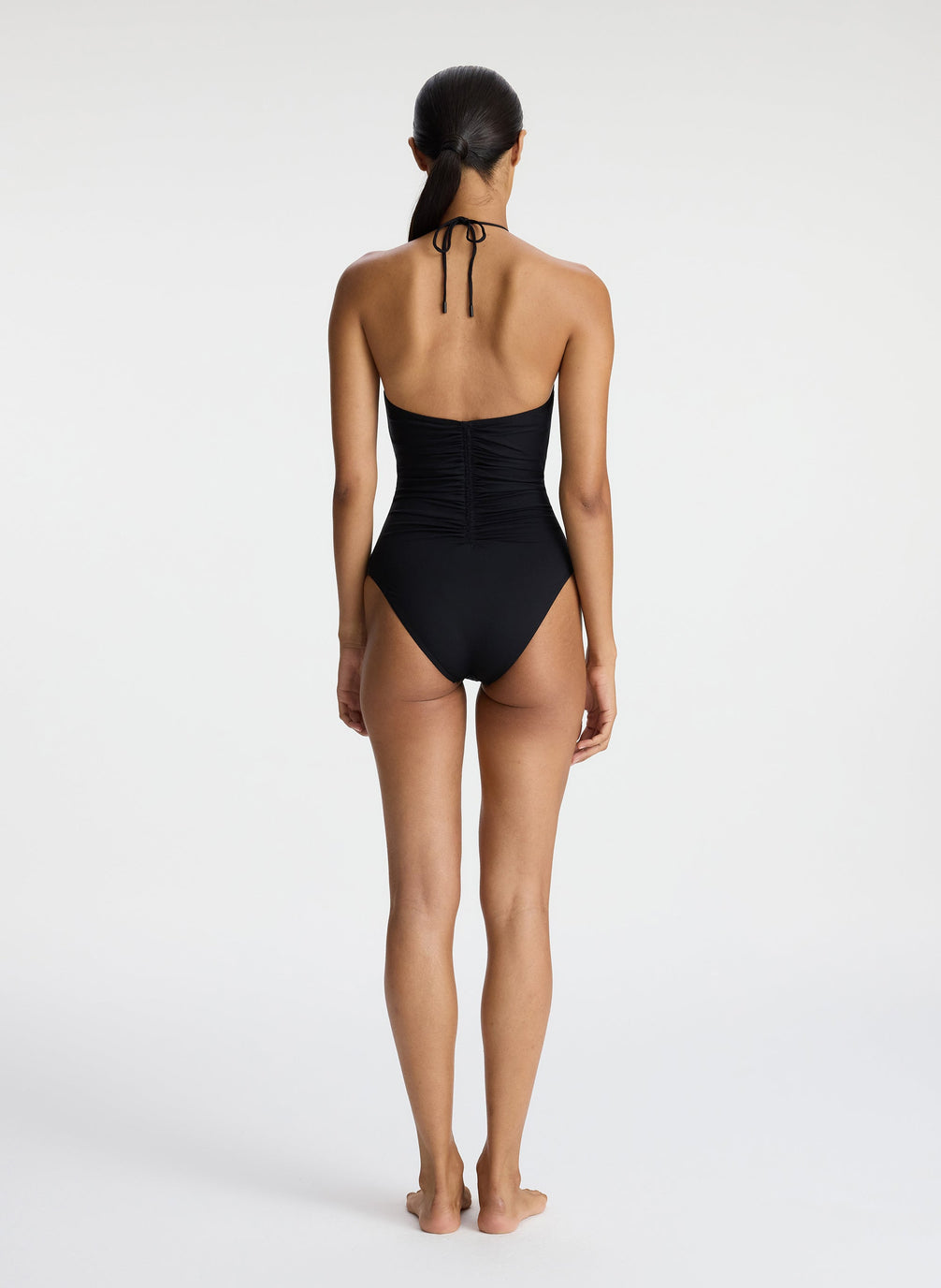back view of woman wearing black halter one piece swimsuit