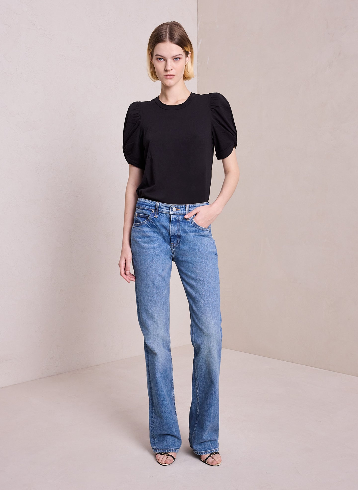 front view of woman wearing black puff sleeve tshirt and light blue wash denim jeans