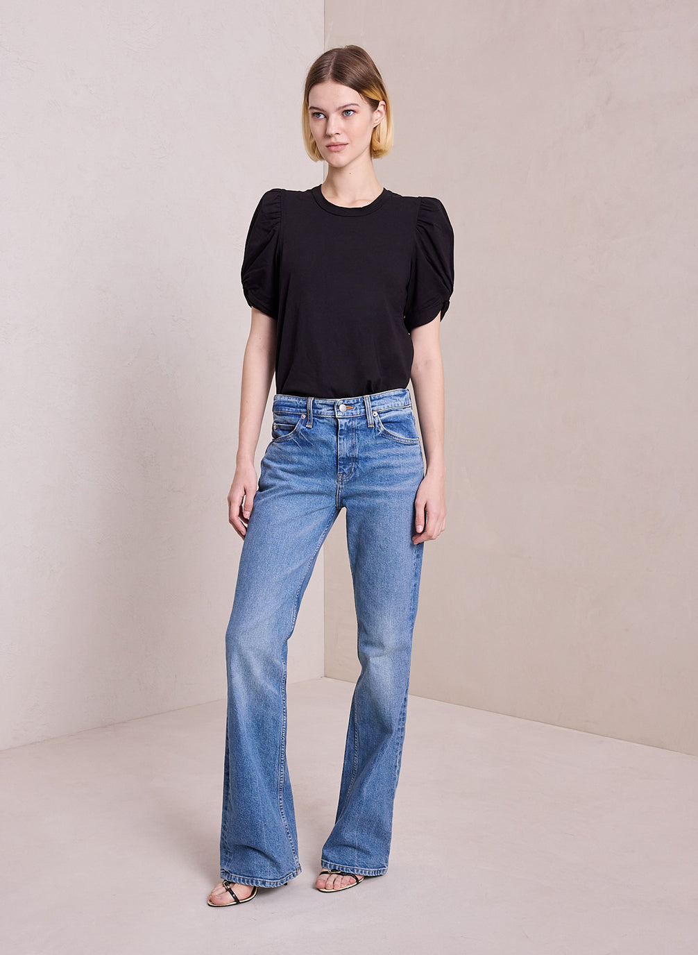 front view of woman wearing black puff sleeve tshirt and light blue wash denim jeans