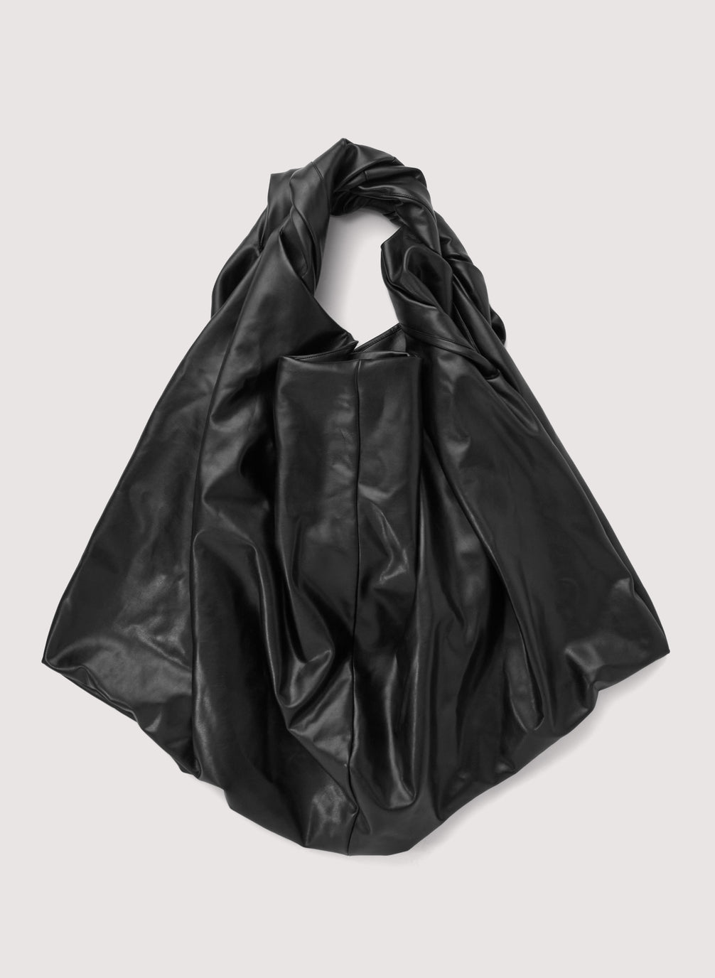 flat lay view of black vegan leather medium length top handle bag with large rectangular base