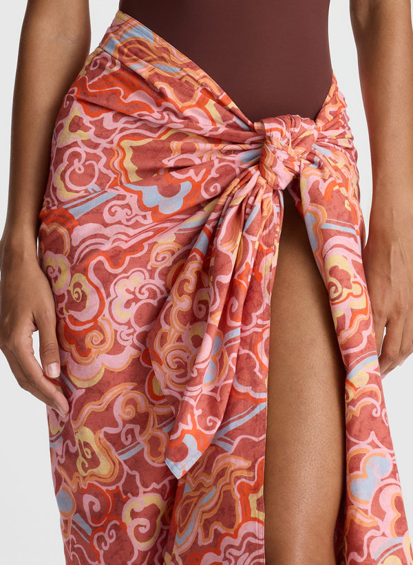 detail view of woman wearing brown one piece swimsuit and multicolor sarong
